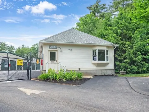 Small rental office building and black security gate in Cape Neddick, ME, next to Storage Star entrance with trees