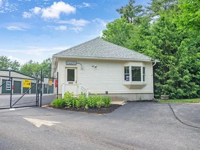 Small rental office building and black security gate in Cape Neddick, ME, next to Storage Star entrance with trees