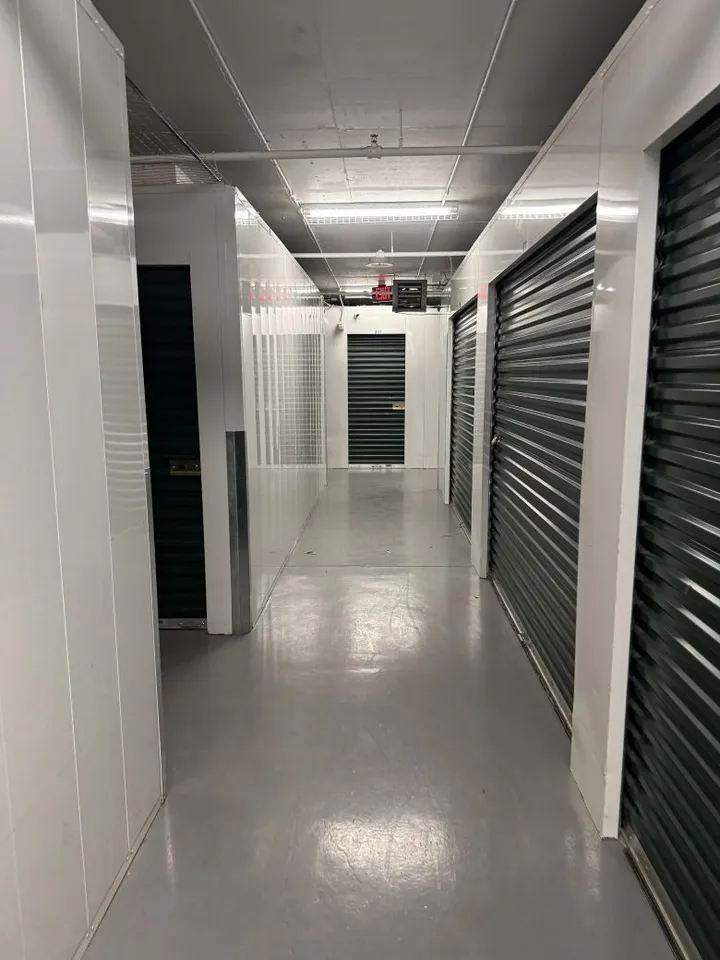 A hallway depicting several indoor climate-controlled storage units in Avon at 910 Nottingham Rd with green roll-up doors