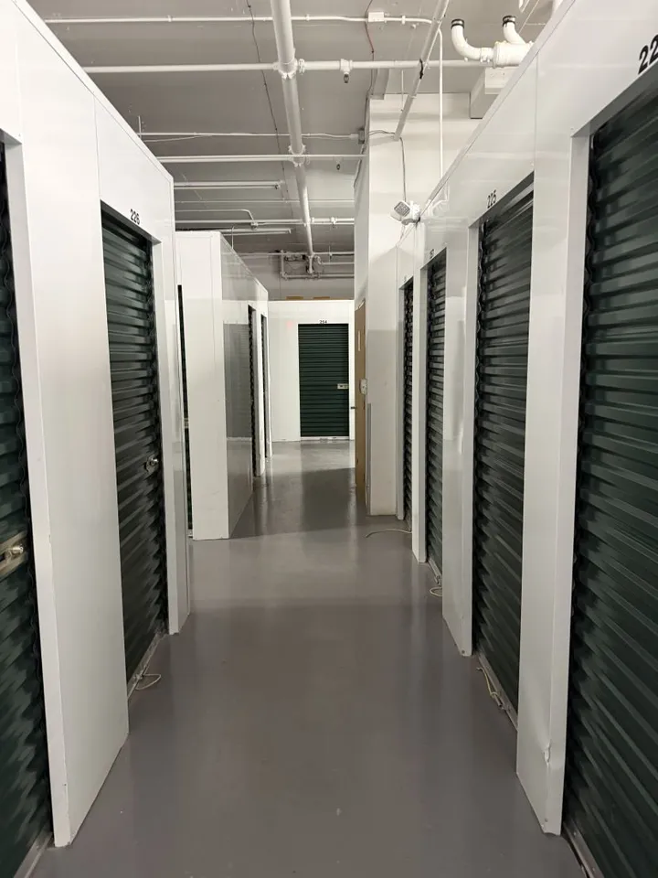 Hallway of indoor climate-controlled storage units in Avon, CO, at 910 Nottingham Rd, with green roll-up doors on both sides