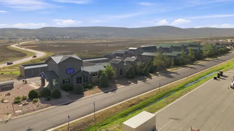 Aerial view of Storage Star Self-Storage in Park City, UT, featuring climate-controlled storage and drive-up storage buildings with green metal roofs near an open valley and mountains