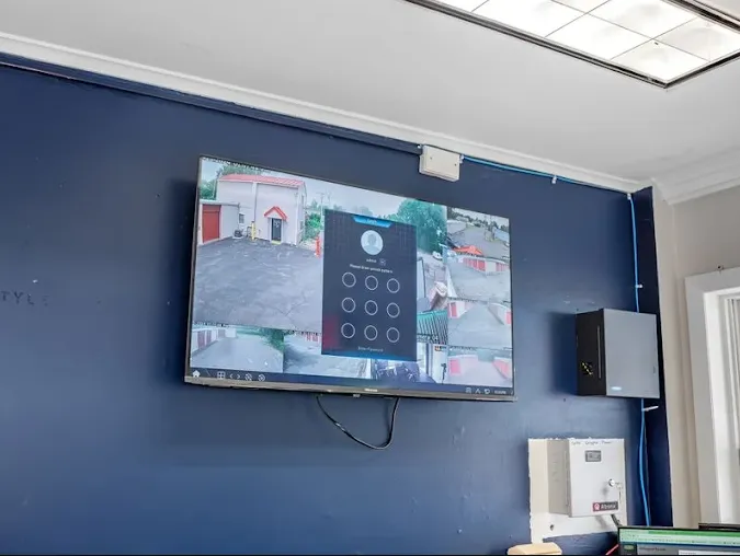 A wall-mounted security monitor displays multiple live camera feeds of Storage Star facility driveways and storage units in Cohoes, NY