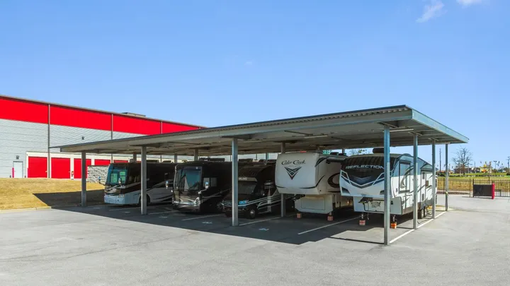 Covered RV storage in North Augusta on Cork Tree Bnd, featuring motorhomes and fifth-wheel campers parked under a metal canopy in an outdoor paved lot
