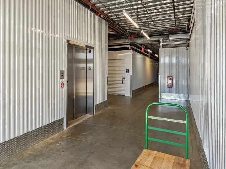 Brightly lit interior hallway at Storage Star Self-Storage in North Augusta with an elevator, white corrugated walls, and a moving cart