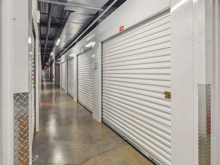 Brightly lit indoor climate-controlled storage in North Augusta on Cork Tree Bend, featuring white corrugated roll-up doors and polished concrete floors