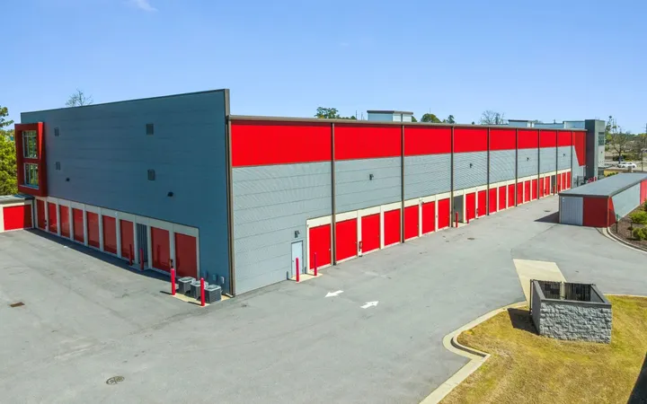 Exterior view of a multi-story storage building with grey siding, red accents, and many red roll-up doors at Storage Star Self-Storage in North Augusta, SC