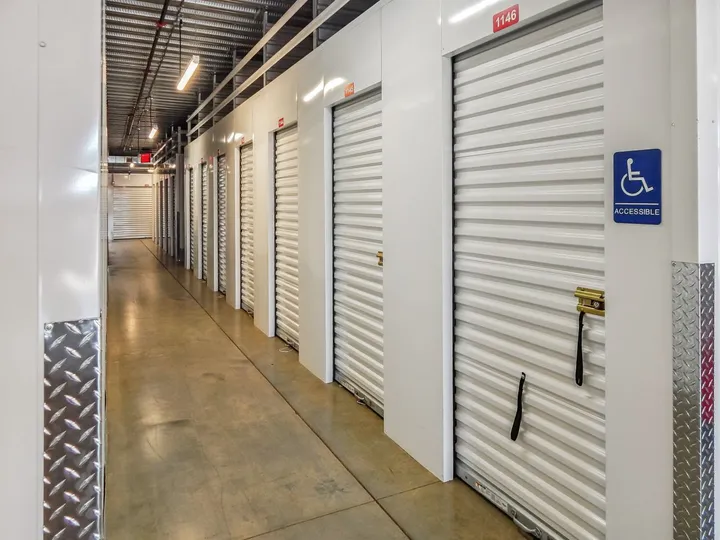 Hallway of indoor climate-controlled storage in North Augusta on Cork Tree Bnd with rows of white roll-up doors and an accessible unit sign