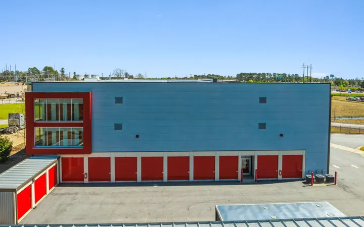 Large grey multi-story storage facility with glass windows on the side and red roll-up drive-up storage units in North Augusta on Cork Tree Bnd