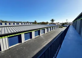 An upper-level view from a balcony of walk-up units looking down on an aisle of drive-up storage units in Marco Island on E Elkcam Cir