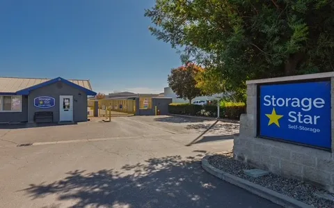 Front entrance of the Woodland Storage Star on Matmor Rd featuring a branded monument sign in front of a paved parking lot and gray office building with a yellow access gate.