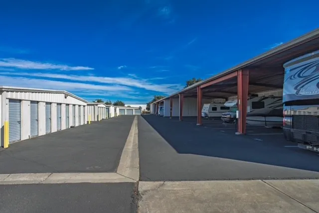 Outdoor covered vehicle storage and RV storage in Woodland, CA, on Matmor Rd along a paved driveway across from drive-up units with gray roll-up doors