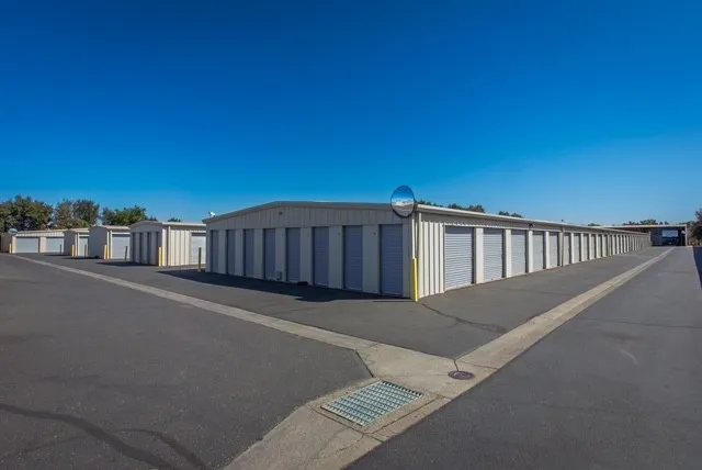 Outdoor drive-up storage units in Woodland on Matmor Rd, featuring long rows of white buildings with gray roll-up doors and asphalt driveways