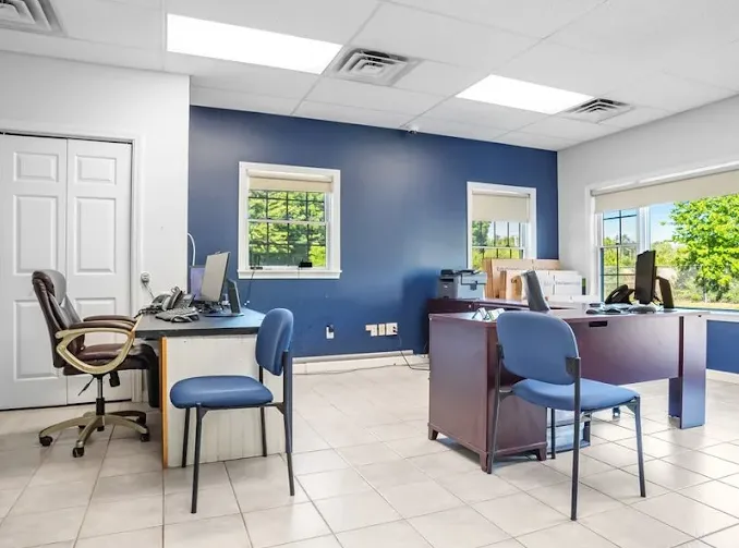 A storage facility rental office featuring desks with computers, chairs, and a blue accent wall