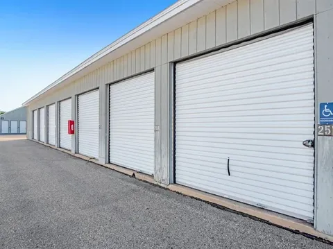 Outdoor drive-up Storage Star self-storage facility featuring a row of white roll-up doors and asphalt driveway