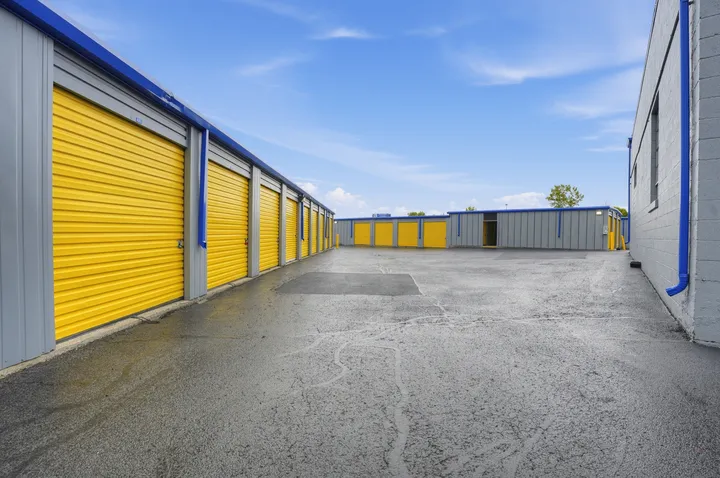 Rows of outdoor drive-up storage units in Albany on Central Ave with yellow roll-up doors under a blue sky