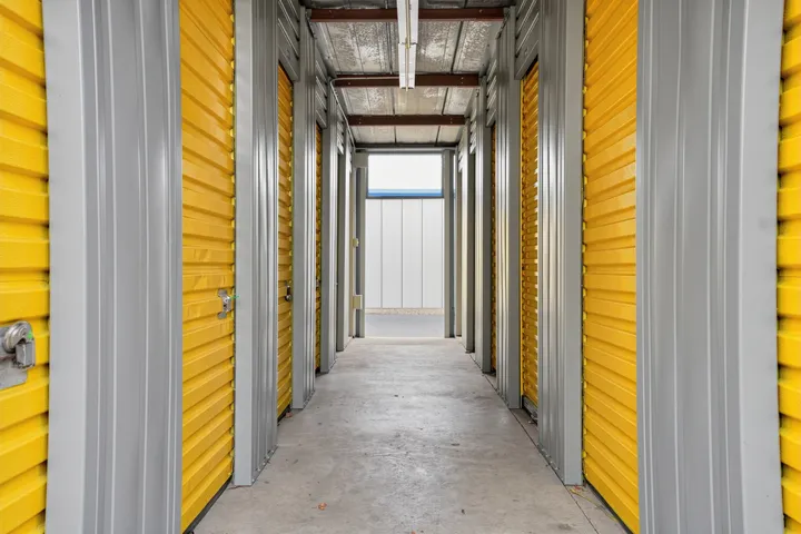 Hallway of indoor storage in Albany on Central Ave featuring rows of yellow roll-up doors and gray metal trim under overhead lighting