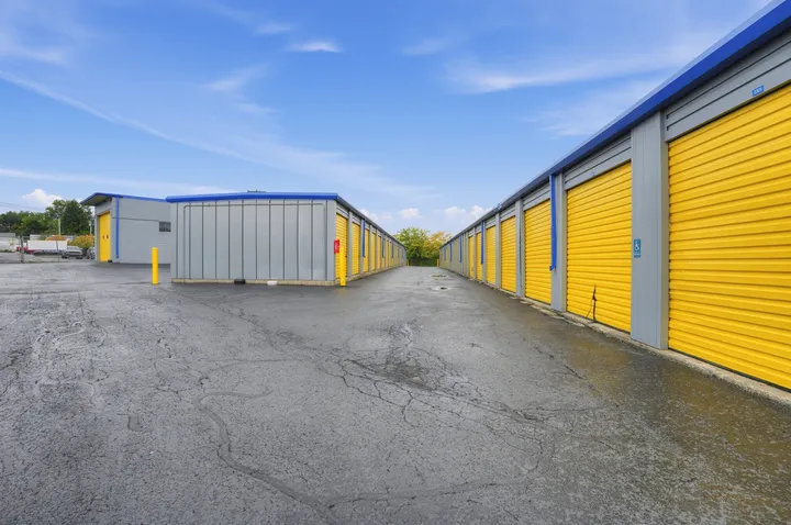 Outdoor drive-up storage units in Albany at 1025 Central Ave, featuring long rows of yellow roll-up metal doors and wide asphalt driveways