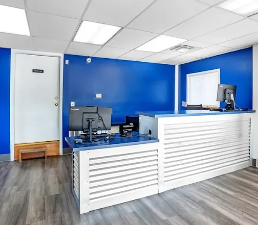 Office interior at Storage Star Self-Storage in Albany, featuring a white slatted front desk with computers against bright blue walls