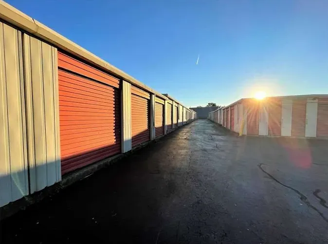 Rows of outdoor drive-up storage units in Albany on Central Ave with orange roll-up doors under a bright sun and blue sky