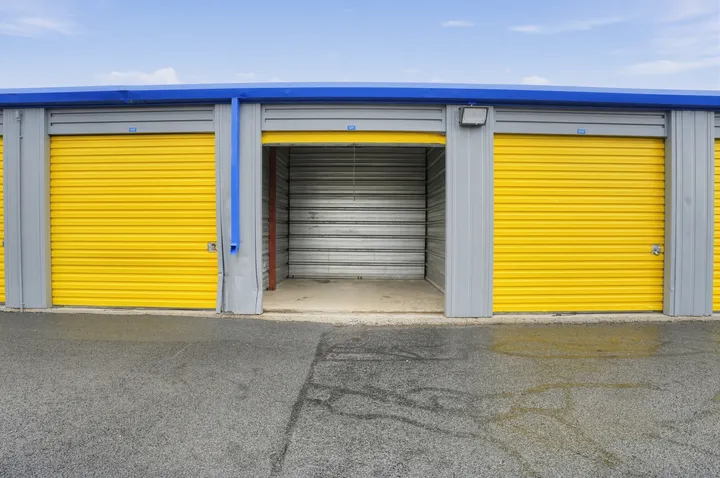 Row of outdoor storage units in Albany on Central Ave with yellow roll-up doors and one open unit showing a metal interior