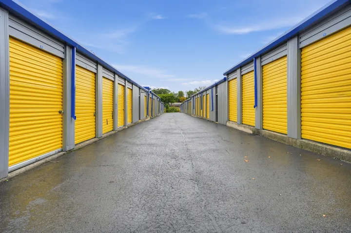 Outdoor drive-up storage units in Albany at 1025 Central Ave, featuring yellow roll-up metal doors and wide asphalt driveways