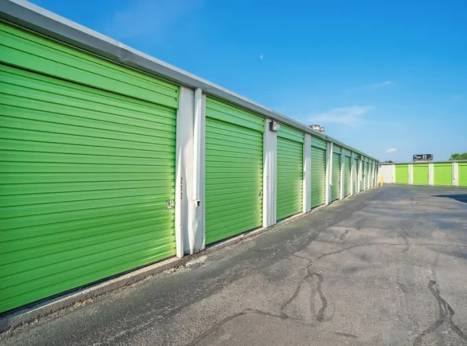 Outdoor drive-up storage units in Albany at 1025 Central Ave, featuring long rows of lime green roll-up metal doors and wide asphalt driveways