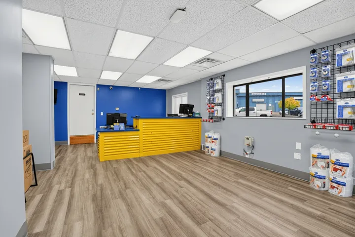 Office interior at Storage Star Self-Storage in Albany, featuring a yellow slatted front desk with computers against bright blue and gray walls with moving supply displays