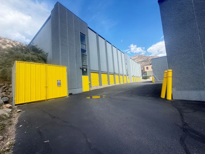 A row of drive-up storage units in Avon, CO, with yellow roll-up doors along a paved asphalt driveway
