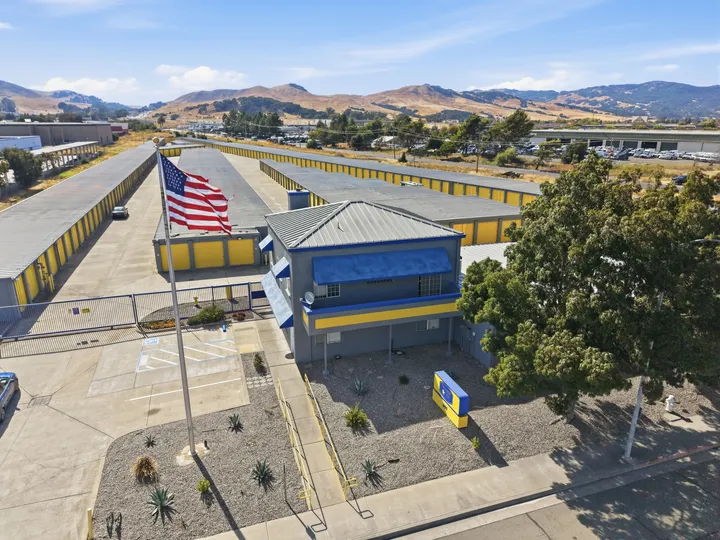 High-angle view of Storage Star Self-Storage in Fairfield on Lopes Rd with yellow drive-up units, an American flag, and hills in the background