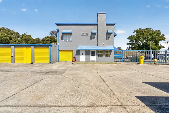 Gray two-story storage office with blue awnings, a gated entrance, and yellow drive-up units in Fairfield on Lopes Rd