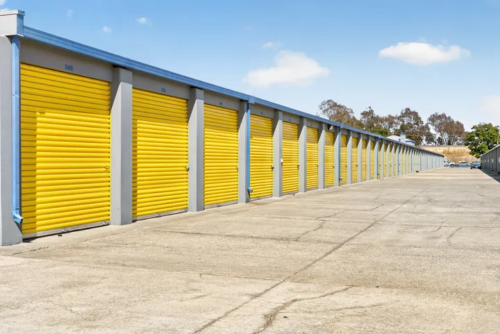 Outdoor drive-up storage units in Fairfield on Loped Rd with bright yellow roll-up doors and a concrete driveway under a blue sky
