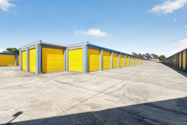 Outdoor row of gray drive-up storage units in Fairfield on Lopes Rd with yellow roll-up doors along a concrete driveway