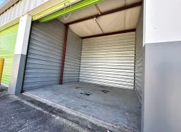 An open drive-up self-storage unit with a concrete floor and a lime green roll-up door