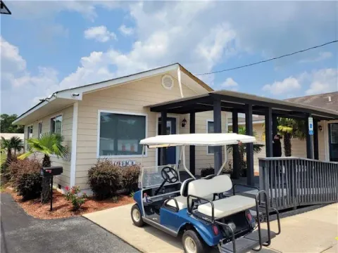 A blue golf cart parked in front of a tan storage facility office with a wooden ramp at Storage Star Self-Storage in Little River on SC-17