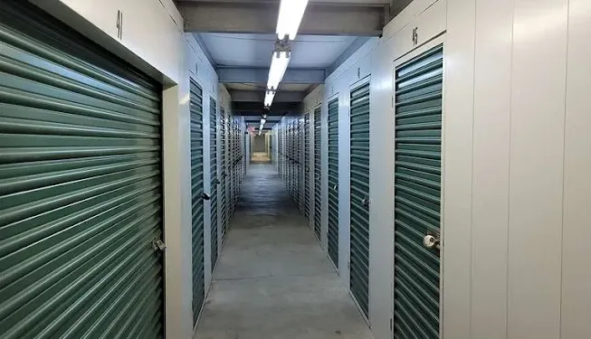 A brightly lit hallway lined with green roll-up climate-controlled storage units in Holtsville on Waverly Ave