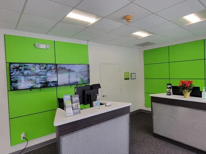 Two modern reception desks in the rental office at Storage Star Self-Storage in Holtsville on Waverly Ave, with green wall panels and security monitor displays