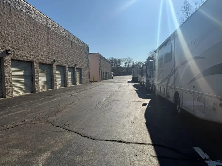 Drive-up storage units along an asphalt lot with large recreational vehicles parked in outdoor spaces