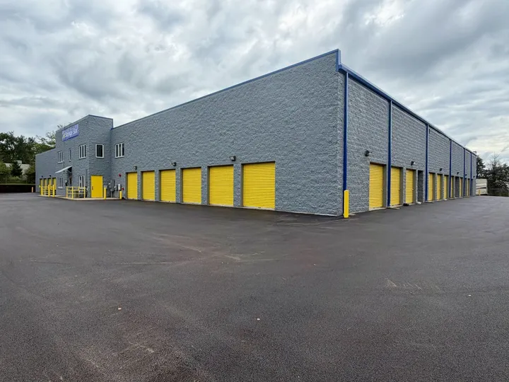 Large gray stone storage building with numerous yellow drive-up units in West Chicago on Garys Mill Rd along a paved driveway
