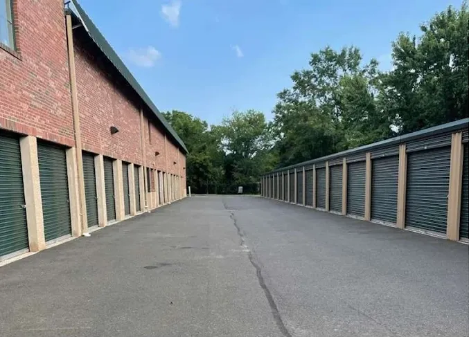 Long rows of outdoor drive-up storage units in Freehold, NJ, with green roll-up doors and a paved driveway