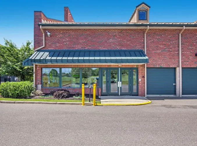 Storage Star rental office in Freehold, NJ, with glass doors, a green awning, yellow bollards, and drive-up storage units
