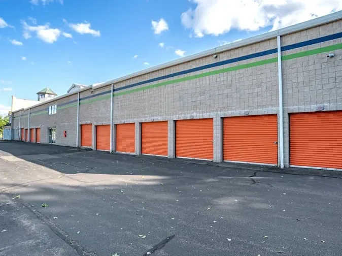 Exterior view of Storage Star North Brunswick featuring a row of orange drive-up unit doors and asphalt pavement