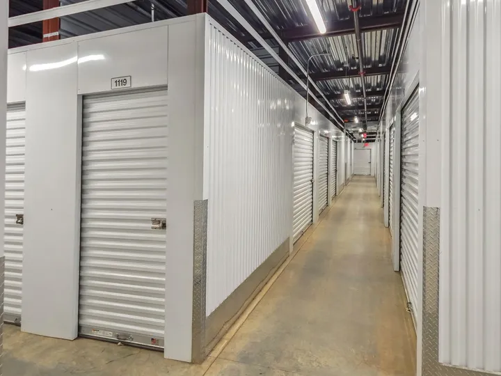 Indoor climate-controlled storage in Augusta on Cooper Dr, with white roll-up doors, numbered units, and overhead fluorescent lighting