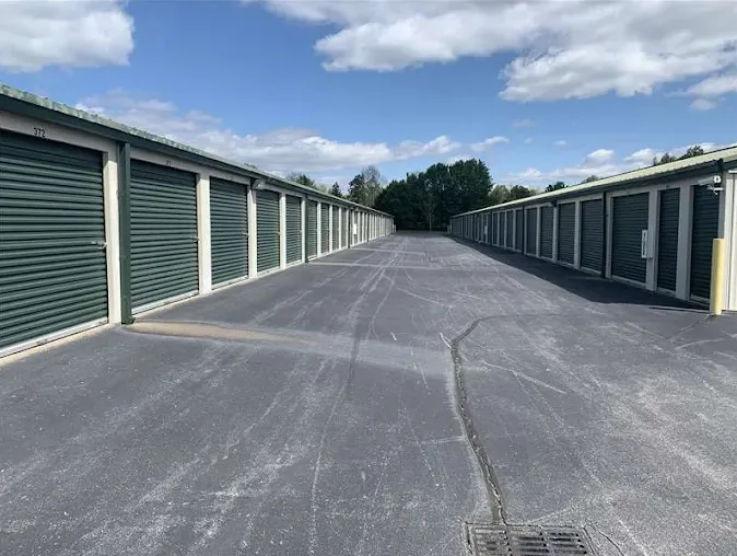 Long rows of outdoor drive-up storage units at Storage Star on Westpoint Boulevard with green roll-up doors and asphalt paving under a blue sky