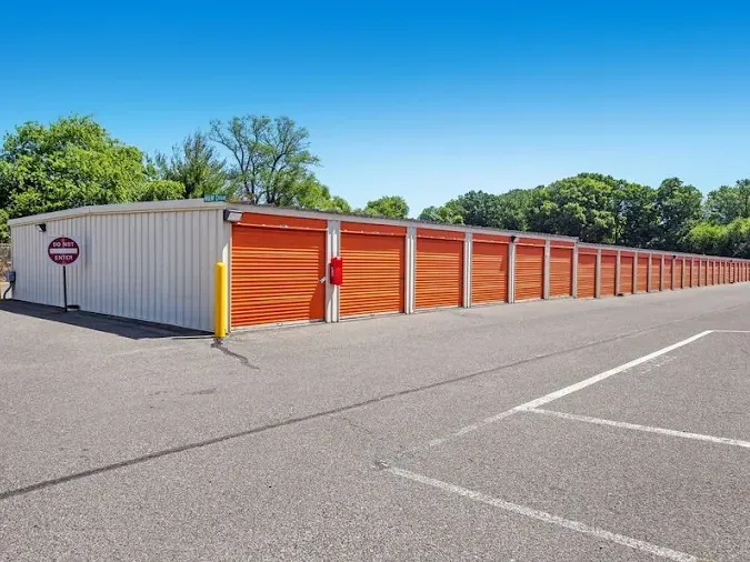 Long row of orange drive-up storage units in Westville, NJ, beside a paved parking lot