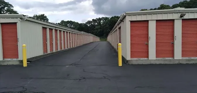 Outdoor drive-up storage in Schenectady on Altamont Ave, with two rows of drive-up units featuring red roll-up doors and yellow bollards