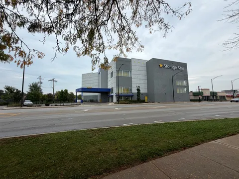 Exterior view across the street of a gray multi-story Storage Star facility on N McCormick Blvd with a blue covered loading bay