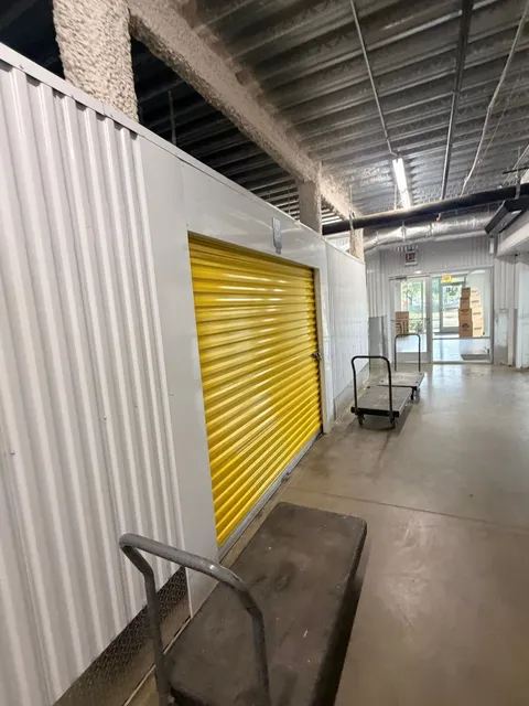 Hallway of climate-controlled storage units in Chicago, IL, with yellow roll-up doors and moving carts