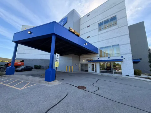 Exterior of a multi-story storage building featuring a blue loading canopy and a glass-front office entrance at Storage Star on N McCormick Blvd