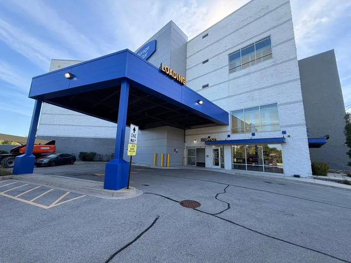Exterior of a multi-story storage building featuring a blue loading canopy and a glass-front office entrance at Storage Star on N McCormick Blvd