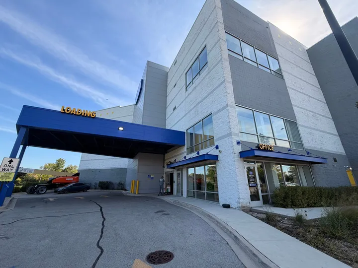 A multi-story storage building with a glass-front office and a blue covered loading area at Storage Star Self-Storage in Chicago on N McCormick Blvd